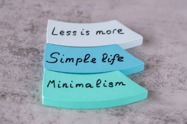 Minimalizm, gri arka plandaki renkli tahta tahtalara siyah harflerle yazılmış daha az hayat kelimesidir..