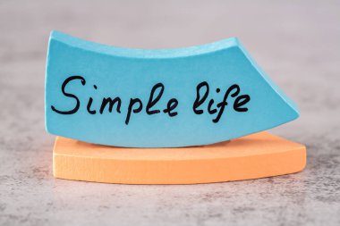 Mavi tahta tahtalara siyah harflerle yazılmış basit hayat sözcükleri gri arka planda duruyor..