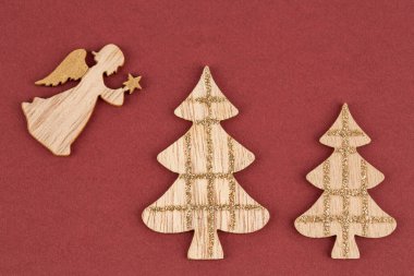 Ahşap melek ve iki köknar ağacı kırmızı arka planda izole edilmiş..