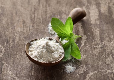 Stevia leaves with powder in wooden spoon clipart