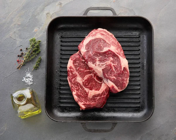 Beefsteak Mit Gewürzen Und Grillpfanne Auf Steinhintergrund lizenzfreie Stockbilder