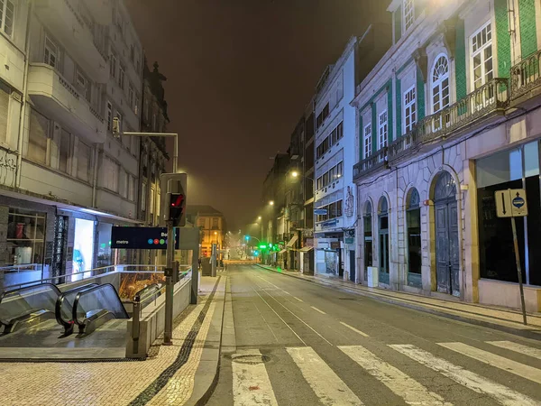 Empty central city street in night fog, metro exit and street lights, crosswalk, Porto, Portugal