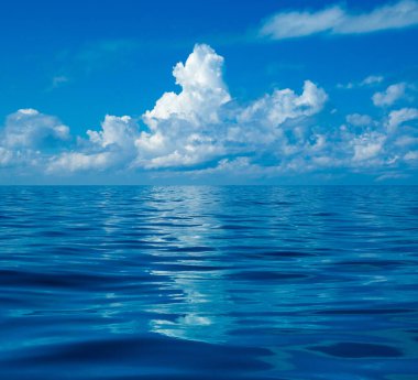 Güzel beyaz bulutların üstünde sakin deniz üzerinde mavi gökyüzü