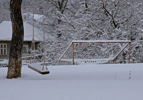 Swing on the tree and soccer goal covered with snow in winter