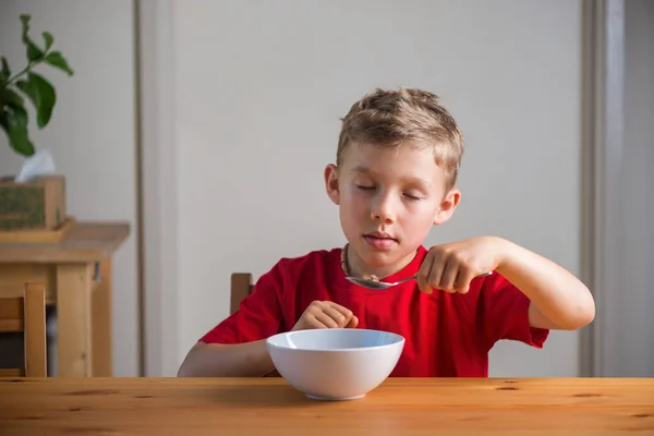 かわいい男の子は朝食にグラノーラを食べる ライフスタイルの肖像画 自然光だ 本物の表現 ロイヤリティフリーのストック写真