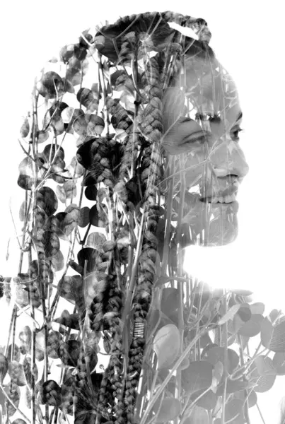 A black and white half profile portrait of a smiling woman with dreadlocks merged with a photo of foliage in double exposure