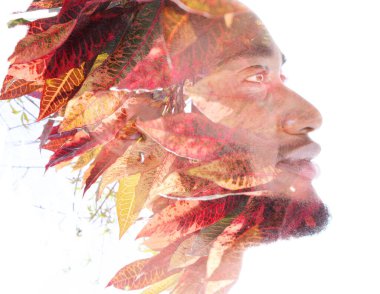 Gülümseyen genç bir adamın profil portresi kırmızı ve sarı yaprakların fotoğrafıyla birleşti.