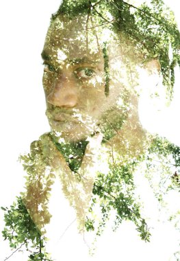 Yakın plan bir portre, elini çenesine dayayan Afro-Amerikan bir adam ve şeffaf bir çift pozlu ağaç yapraklarının fotoğrafı..