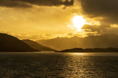 Cruise ship sailing between mountains in Glacier Alley of Beagle channel in Chile at sunrise