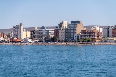 Puerto Madryn, Arjantin - 2 Şubat 2023: Kalabalık plaj ve deniz manzaralı evler ve apartmanlar