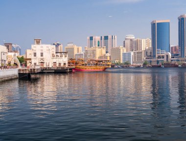 Dubai, BAE 'deki Al Seef rıhtımına yanaşmış büyük dhow tur tekneleriyle Deira' ya doğru dere boyunca bakın.