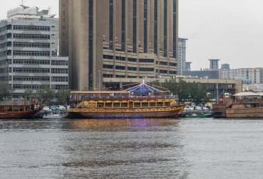 Dubai, BAE 'deki Al Seef rıhtımına yanaşmış büyük dhow tur tekneleriyle Deira' ya doğru dere boyunca bakın.