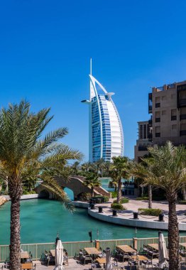 Dubai 'deki Souk Madinat Jumeirah civarındaki bir restoranın arka planında ikonik bir Arap oteli var.