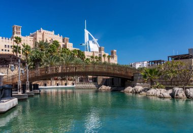 Dubai 'deki Souk Madinat Jumeirah civarındaki bir restoranın arka planında ikonik bir Arap oteli var.