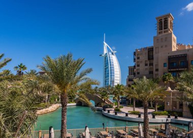 Dubai 'deki Souk Madinat Jumeirah civarındaki bir restoranın arka planında ikonik bir Arap oteli var.