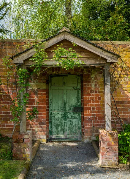 漆成绿色的门和木制门廊 作为砖墙花园的入口 — 图库照片