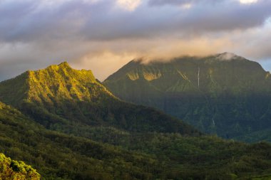 Kauai 'deki Hanalei vadisinin yukarısındaki Na Pali dağları. Güneş batmadan hemen önce çekilmiş bulutları aydınlatan