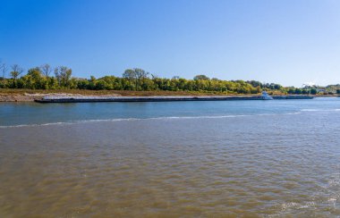 Büyük bir römorkör, Illinois 'in güneyinde Mississippi nehrinde tahıl ürünleriyle sıra sıra mavnaları itiyor.
