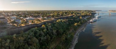 Modern Mississippi yolcu gemisi ve geleneksel nehir teknesi Natchez Mississippi 'deki tepenin altındaki kayalıklara yanaştı.