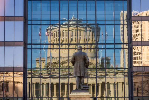 オハイオ州議会議事堂の建物がコロンブス通りを横切るオフィスビルの窓の反射の前にあるマッキンリー記念碑 ストック画像