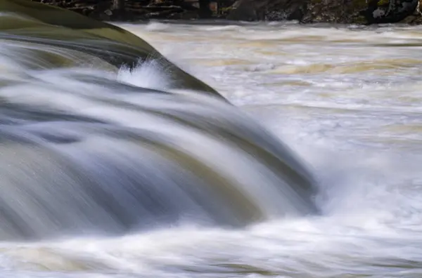 西维吉尼亚州费尔蒙特市附近泰加特河流域瀑布州立公园岩石上涌出的湍急水流模糊了丝般清晰的曝光 图库图片