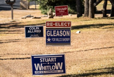 Georgetown, TX - 24 October 2024: Street signs and placards for local democratic candidates with Trump Vance and Ted Cruz signs in background clipart