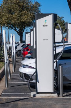 Georgetown, TX - 11 January 2025: Multiple electric cars connected to DC high speed charger at Electrify America public charging unit clipart