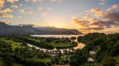 Hawaii, Kauai 'deki görkemli dağların çerçevelediği Hanalei Körfezi' nin bereketli manzarasında gün batımı bulutlarının canlı bir görüntüsü..
