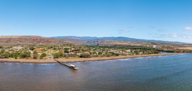 Panoramik hava görüntüsü, Waimea, Kauai 'nin sakin güzelliğini, rıhtımını, sahil şeridini ve berrak gökyüzünün ardındaki manzarayı gösteriyor.