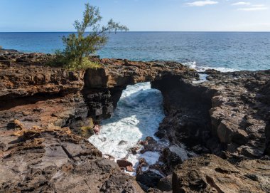 Doğal bir lav kemeri Poipu, Kauai 'deki parlak mavi okyanusa çarpıcı bir kontrast sağlar ve güzel bir sahil manzarası yaratır..