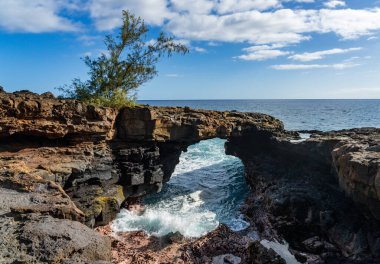 Doğal bir lav kemeri Poipu, Kauai 'deki parlak mavi okyanusa çarpıcı bir kontrast sağlar ve güzel bir sahil manzarası yaratır..