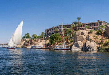 Aswan, Mısır - 4 Kasım 2024: Felucca eski Cataract Oteli 'nin yanındaki Nil' de bir gemi gezisine yelken açıyor.