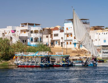 Fil adasındaki Nil kıyılarında, Aswan 'a yanaşmış feribot ve yelkenli tekneleri olan evler.