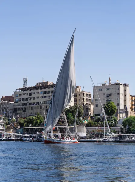 Aswan, Mısır - 4 Kasım 2024: Felucca diğer tur tekneleriyle birlikte Nil üzerinde bir gemi gezisi için rıhtımdan ayrıldı