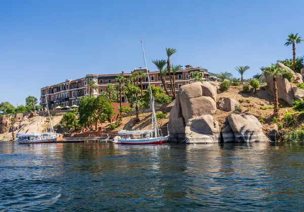 Aswan, Mısır - 4 Kasım 2024: Felucca yelkenli teknesi Eski Katarakt Oteli 'nin yanındaki Nil kıyısına yanaştı