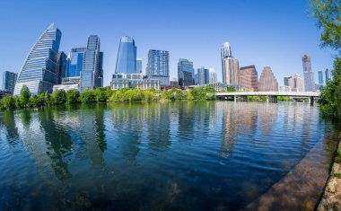 Austin, TX - 10 Nisan 2025: İlkbaharda Colorado nehrinin sakin sularında balık gözü mercekli şehir merkezinin silüeti