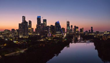 Güneş doğmadan önce, parlak turuncu ve kırmızı gökyüzü Austin Texas 'ın aydınlık şehir siluetinin ardında.