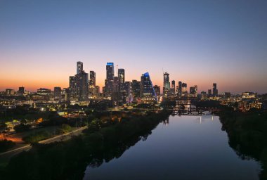 Güneş doğmadan önce, parlak turuncu ve kırmızı gökyüzü Austin Texas 'ın aydınlık şehir siluetinin ardında.