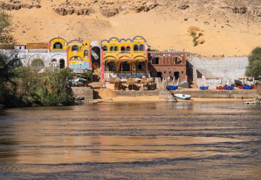 Nil Nehri 'nin hızlı akan suları, Mısır' daki Aswan yakınlarında renkli Nubia otelleri ve barlarıyla.