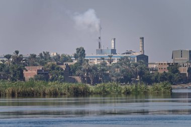 Edfu çelik fabrikasının, sanayi binalarının, bacaların, Nil Nehri 'nden görünen manzarası.