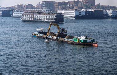 Edfu 'da kalabalık bir limanda Nil yolcu tekneleri rıhtıma yanaştı ve nehirden alüvyon kaldırıyor.