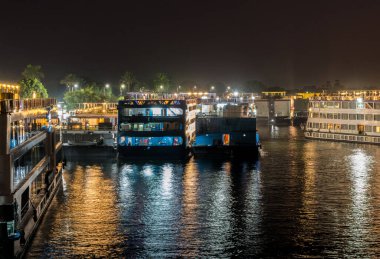 Aydınlatılmış Mısır Nil kruvazörleri tapınak ziyareti için Kom Ombo 'daki nehir kıyısı boyunca istiflendiler.