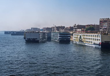 Edfu 'da kalabalık bir liman, Nil yolcu tekneleri yanaştı ve diğerleri Mısır' daki Aswan nehrinden ayrılıyor.