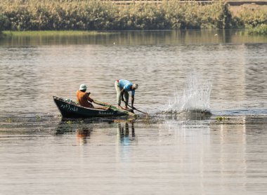 Luxor, Mısır - 1 Kasım 2024: Nil nehrindeki küçük teknelerinde balık ağıyla uğraşan iki adam