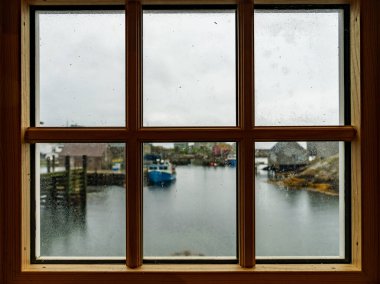 Kanada, Nova Scotia 'da Halifax yakınlarındaki Peggys Koyu' nda yağmurlu bir günde bir pencerenin çerçevesinden dışarı bakıyorum.