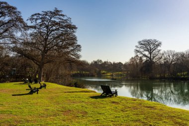 New Braunfels yakınlarındaki sakin Guadalupe nehrinin yanındaki çimenlikte dinlendirici sandalyeler kışın sonlarında