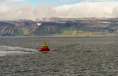 İzlanda 'daki dağların ve denizin dramatik manzarası, Isafjordur yakınlarında, küçük kırmızı balıkçı teknesi yaklaşıyor.