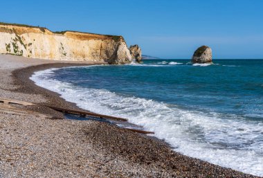 Wight Adası 'ndaki Tatlı Su Koyu' nda küçük dalgalar çakıl taşı plajına çarpıyor.