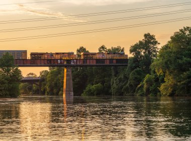 Austin, TX - 13 Ağustos 2025: Çifte lokomotifler Austin Teksas 'ta altın ışıkta tren köprüsünden geçiyor