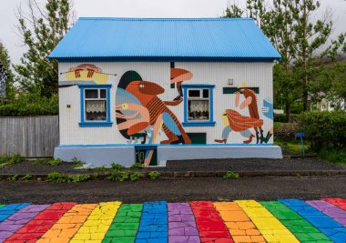 Seydisfjordur, İzlanda - 29 Mayıs 2025: Tepeleri sisle kaplayan ünlü Gökkuşağı Caddesi 'ndeki evdeki duvar resmi